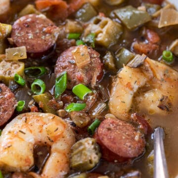 Closeup of a bowl of creole seafood gumbo with shrimp, smoked sausage, and vegetables.