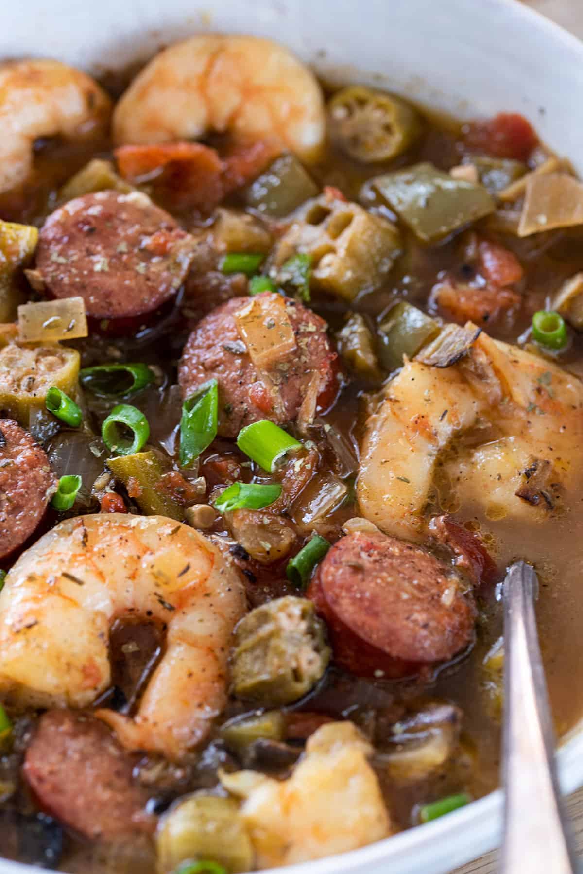 Closeup of a bowl of creole seafood gumbo with shrimp, smoked sausage, and vegetables.