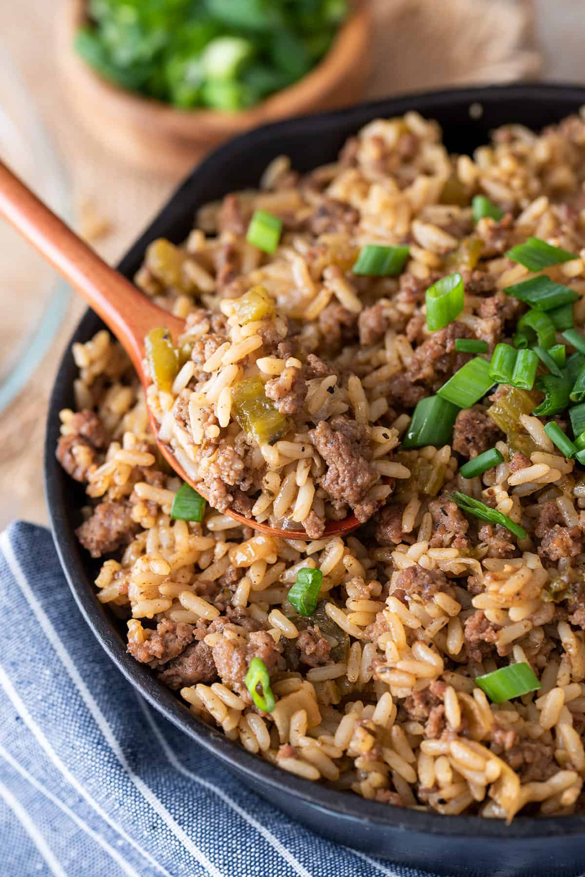 Dirty Rice in a skillet with a spoon and green onions.