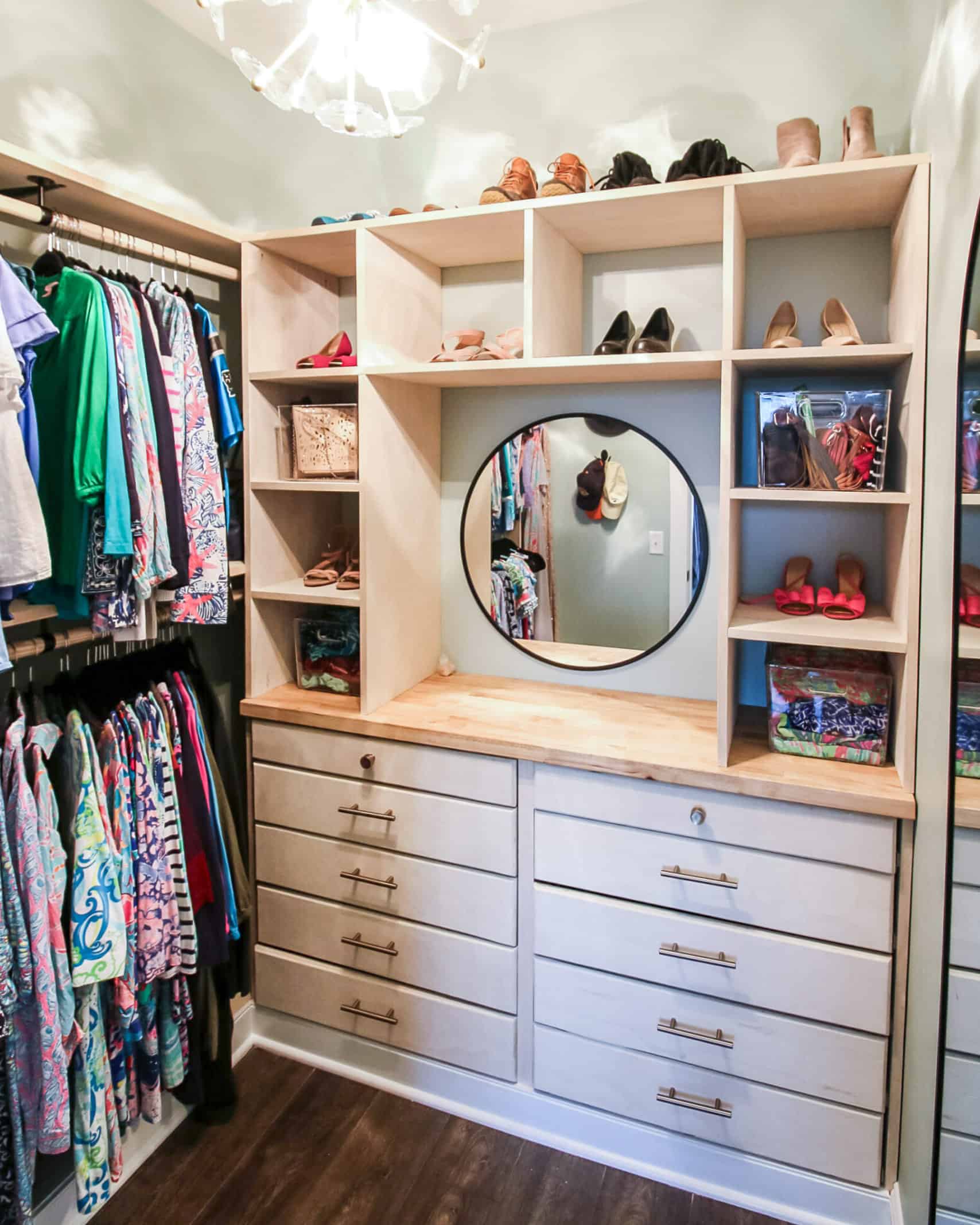 A built in dresser and shelves in a staging closet with hanging clothes on the sides.