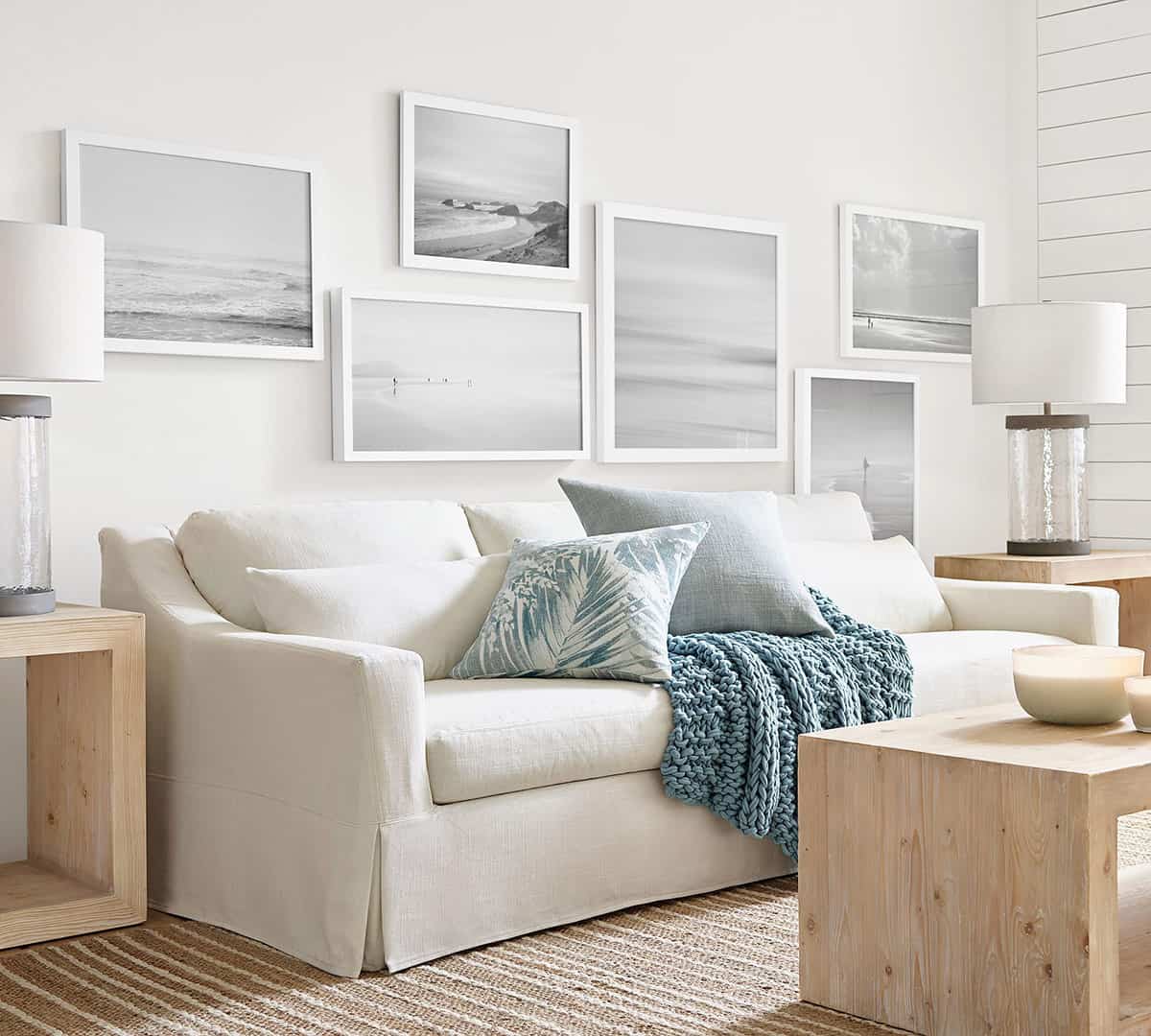 Neutral beige living room with seascape gallery wall art above the slipcovered couch.