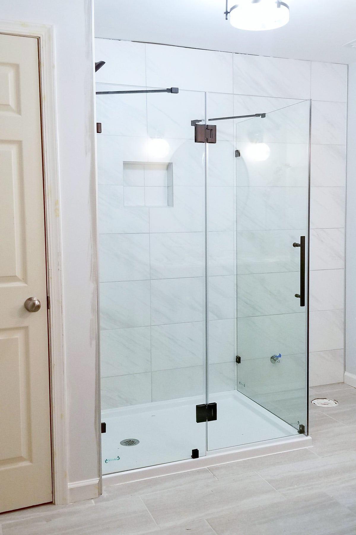 A frameless shower in a fully tiled bathroom.