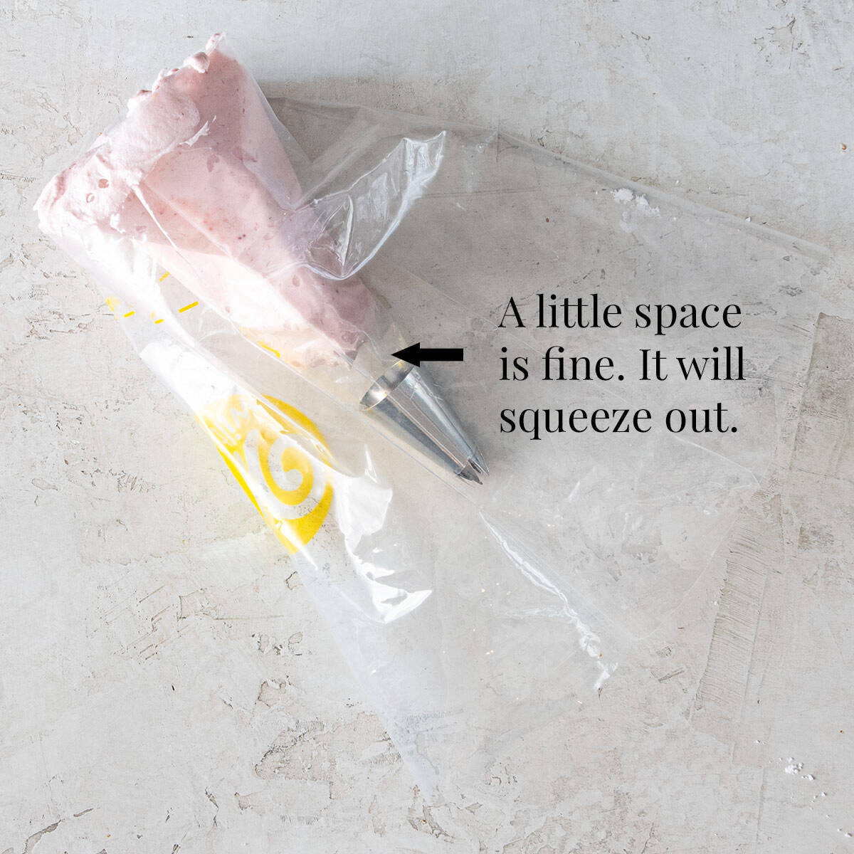 Half full piping bag of Strawberry Cream Cheese Frosting with tip attached.