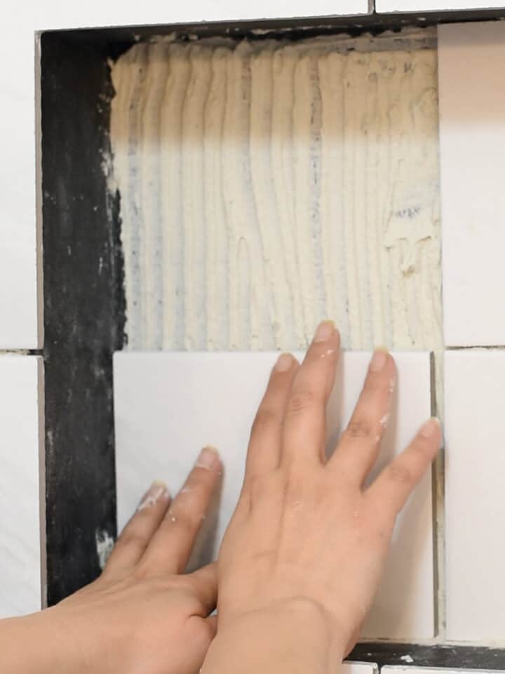 Woman adding tile to a shower nice.