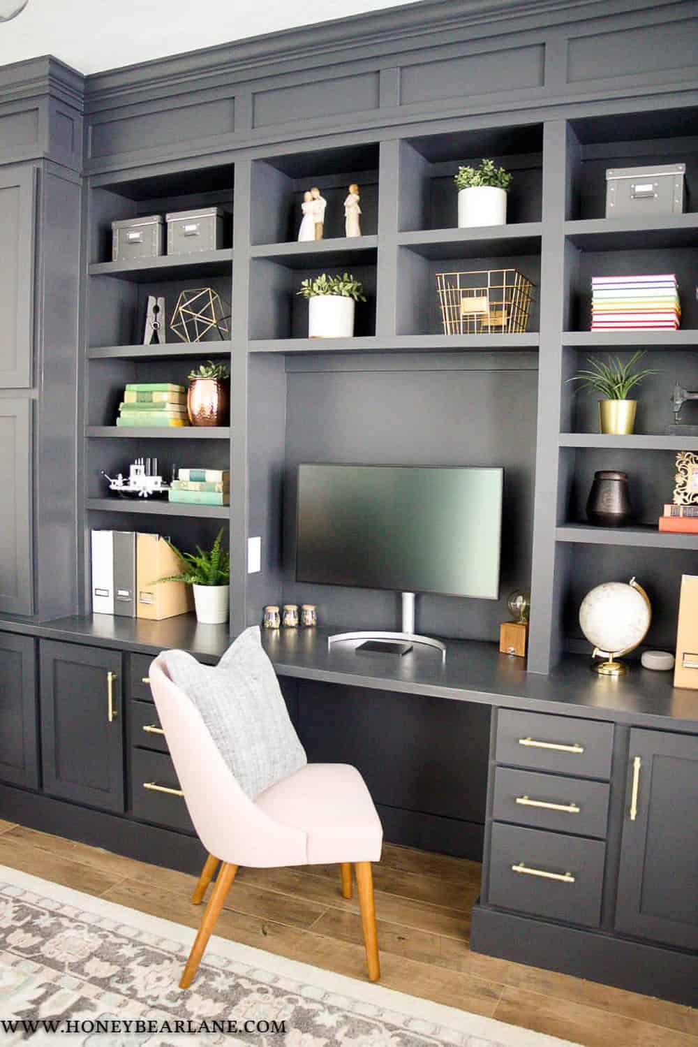 Dark grey bookshelves decorated with books, computer, and accents to show an organized space.