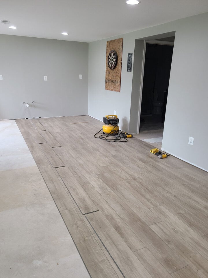 Basement with concrete slab subfloor having vinyl plank flooring installed on top.