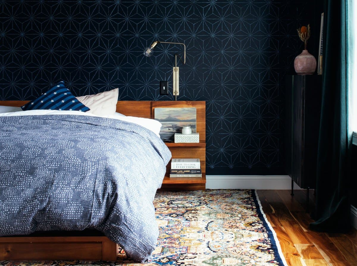 Navy stenciled bedroom with blue comforter and modern Scandinavian furniture in a minimalism look.