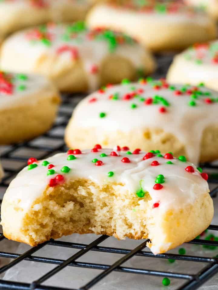 Close up of a sour cream cookie with red and green sprinkles and a bite taken out.