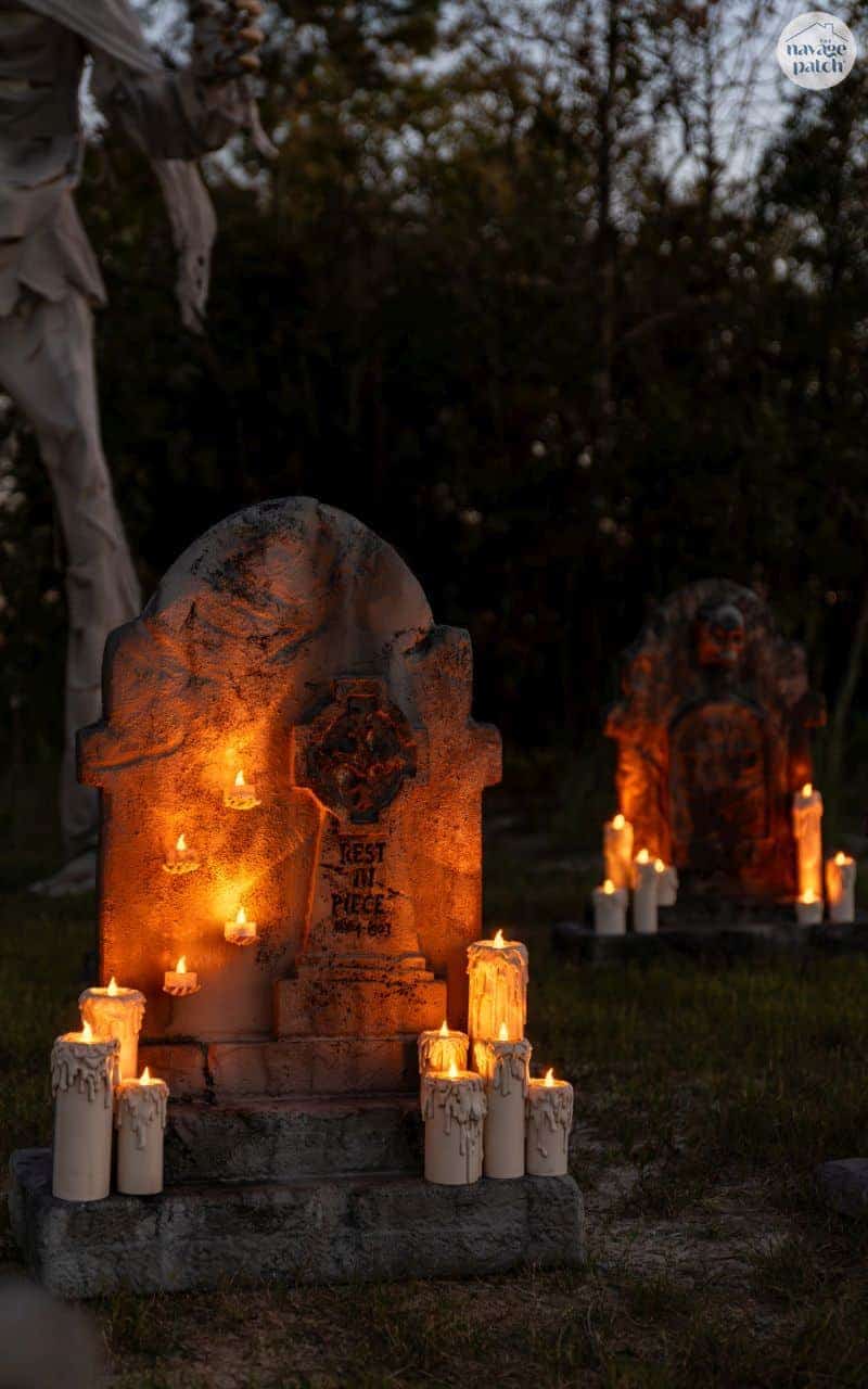 DIY Halloween cemetery in wooded area with faux headstone and faux lit candles.