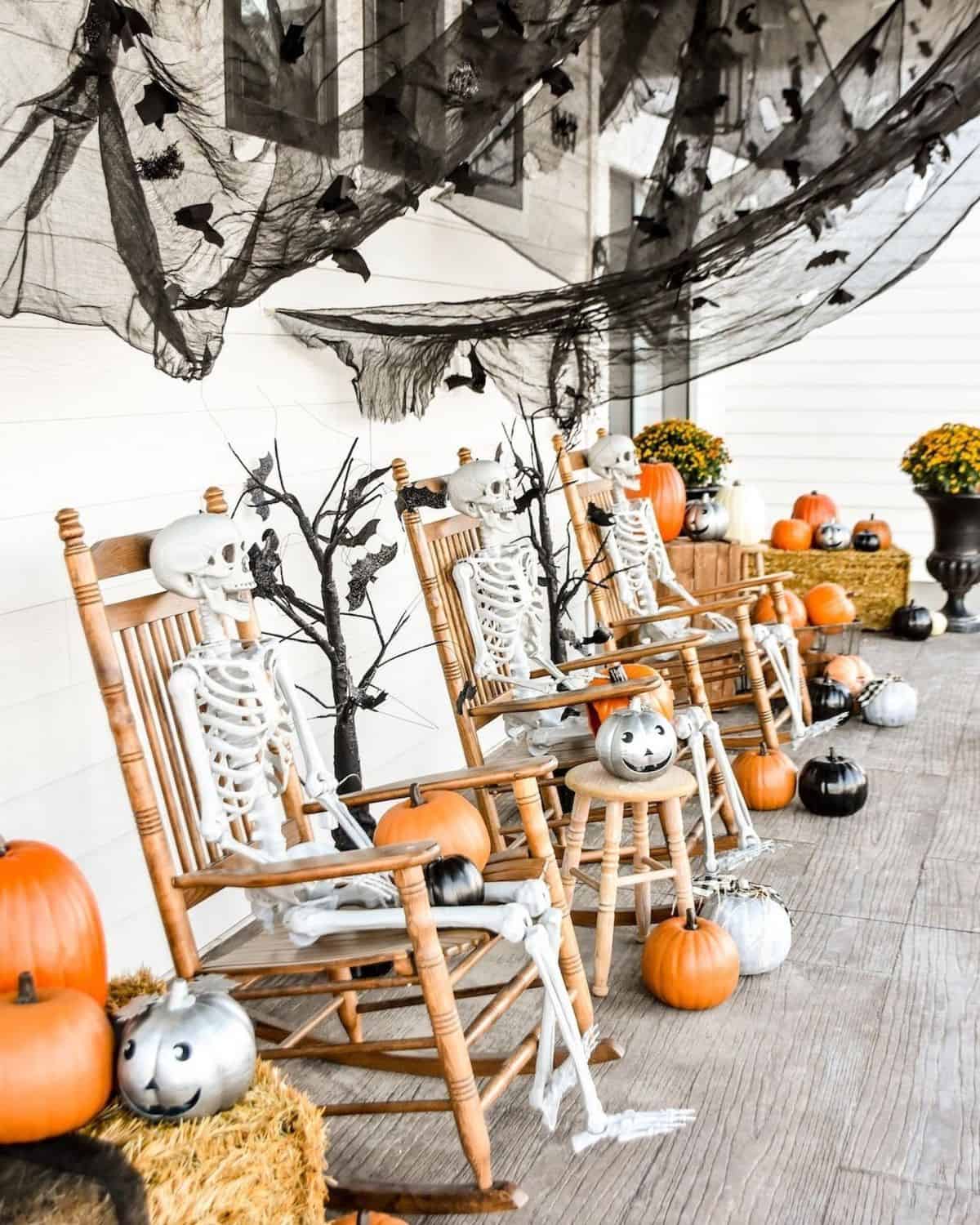 Front porch features skeletons, lacquered black pumpkins, and a flock of tricky bats which cast a spooky vibe while traditional fall elements such as mums and haybales are a visual treat.