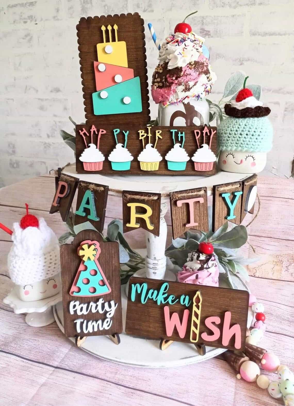 A cupcake stand decorated for a birthday party with small signs, candles, and ice cream motif.