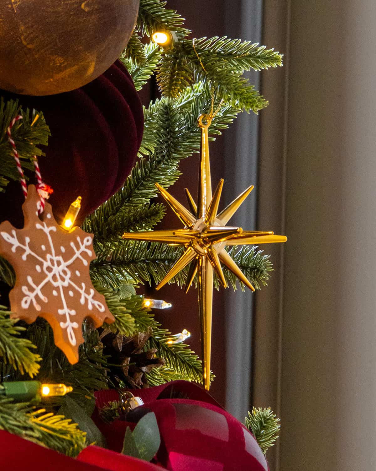 A shiny gold star of Bethlehem ornament on a dark Christmas tree.