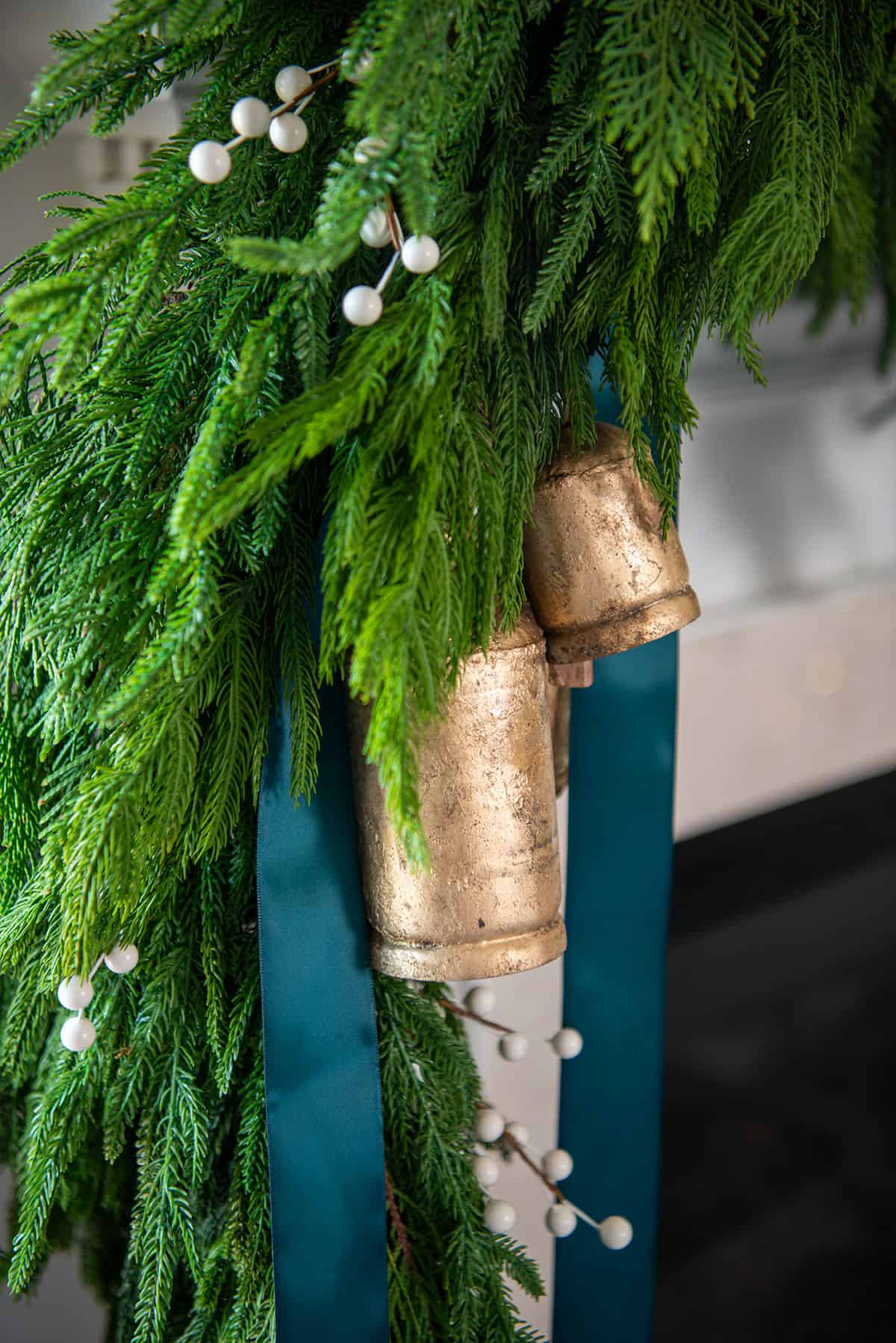 Brass bells and emerald green ribbon in garland on a Christmas garland for a cottage style.