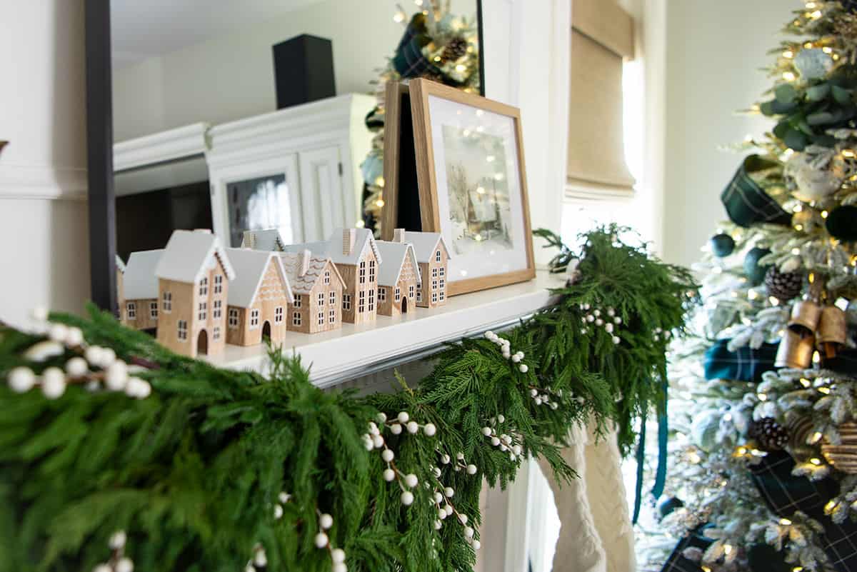 Side view of a cottage style Christmas decorations with droopy garland draped across a white mantel.