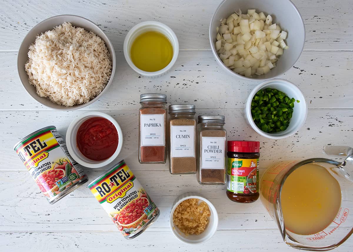 Ingredients to make slow cooker Mexican rice including spices, basmati rice, onions, peppers, and chicken broth.