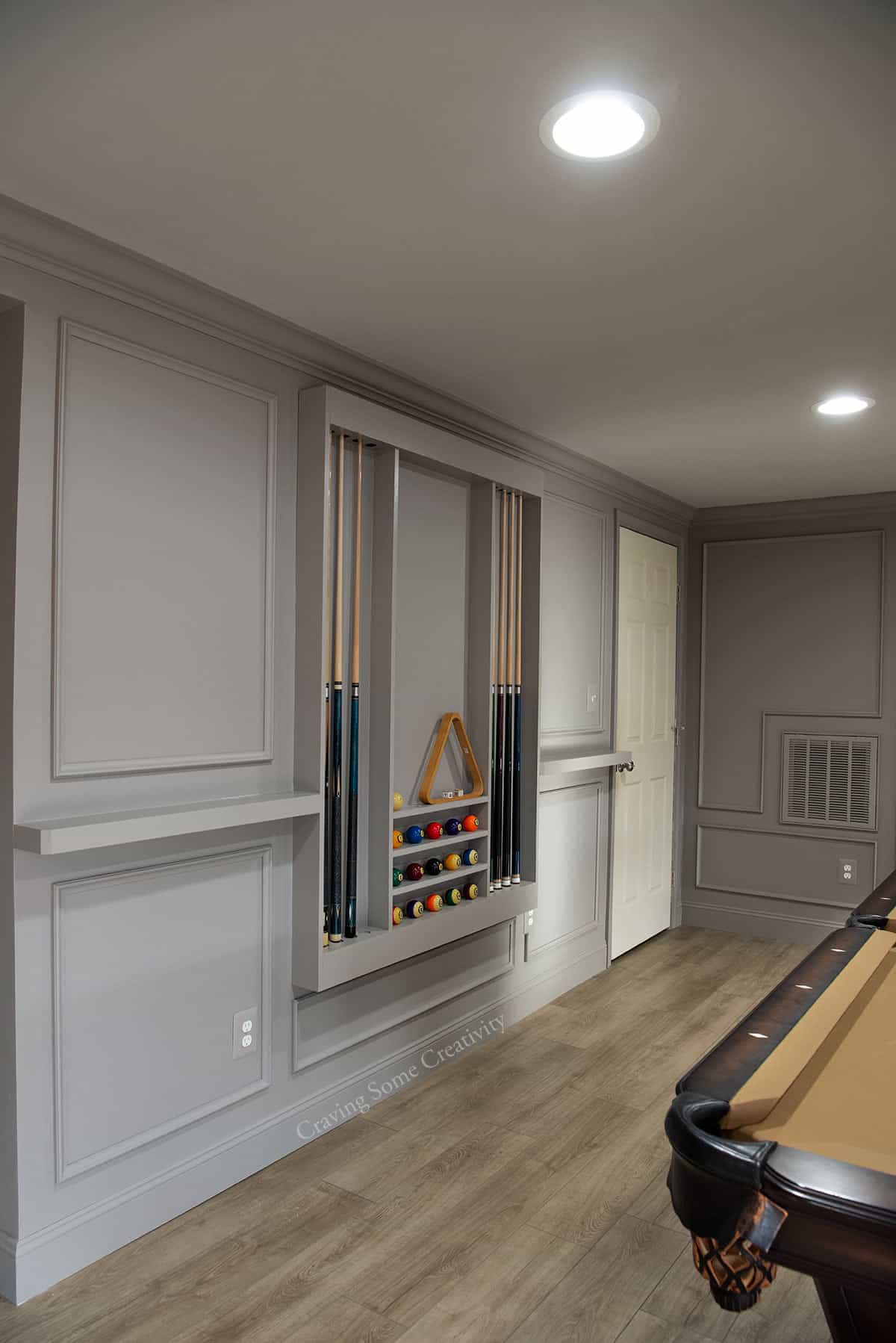 A basement wall with a door, pool rack, and shelves