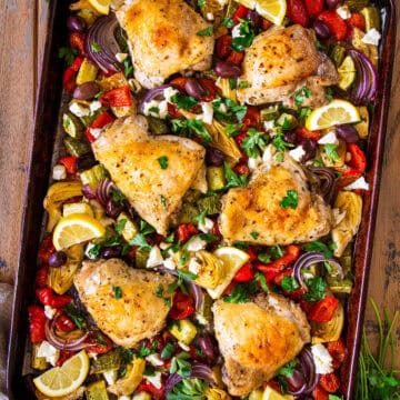 Overhead of chicken and Greek vegetables laid out on a sheet pan after baking.
