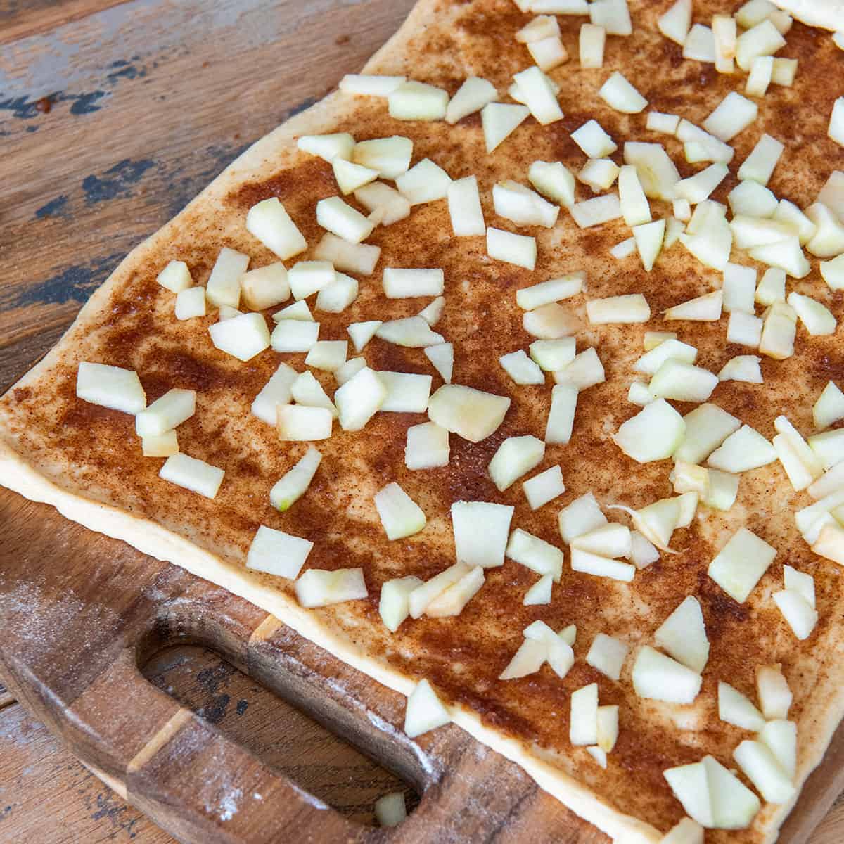 Diced apple sprinkled over a rolled out dough.