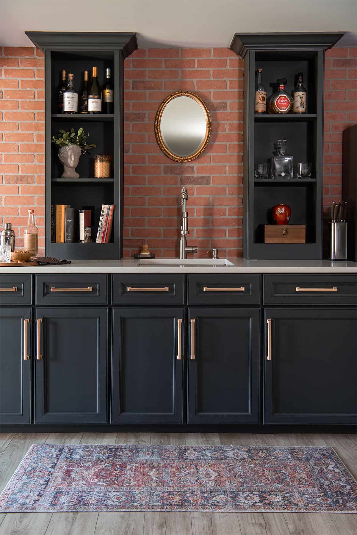 Moody basement wet bar with dark academia vibes and liquor cabinet with faux brick wall behind.