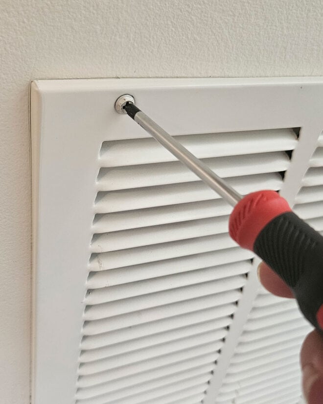 Removing an air return through unscrewing large screwheads around the frame.