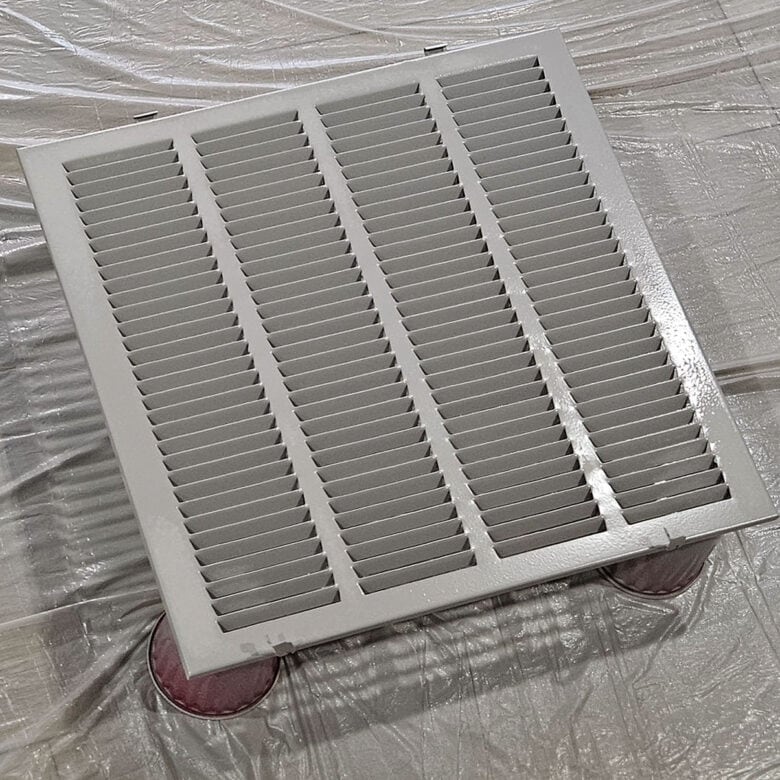 A freshly painted air return on the floor drying.